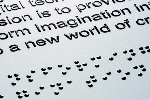 Photo: "Imagination... a new world" Close-up photograph of a page with tactile text and Braille which contains the excerpt: "Imagination... a new world"